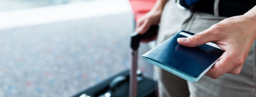 Person holding travel documents with suitcase