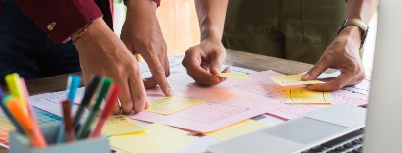 Two people touching post it notes with laptop